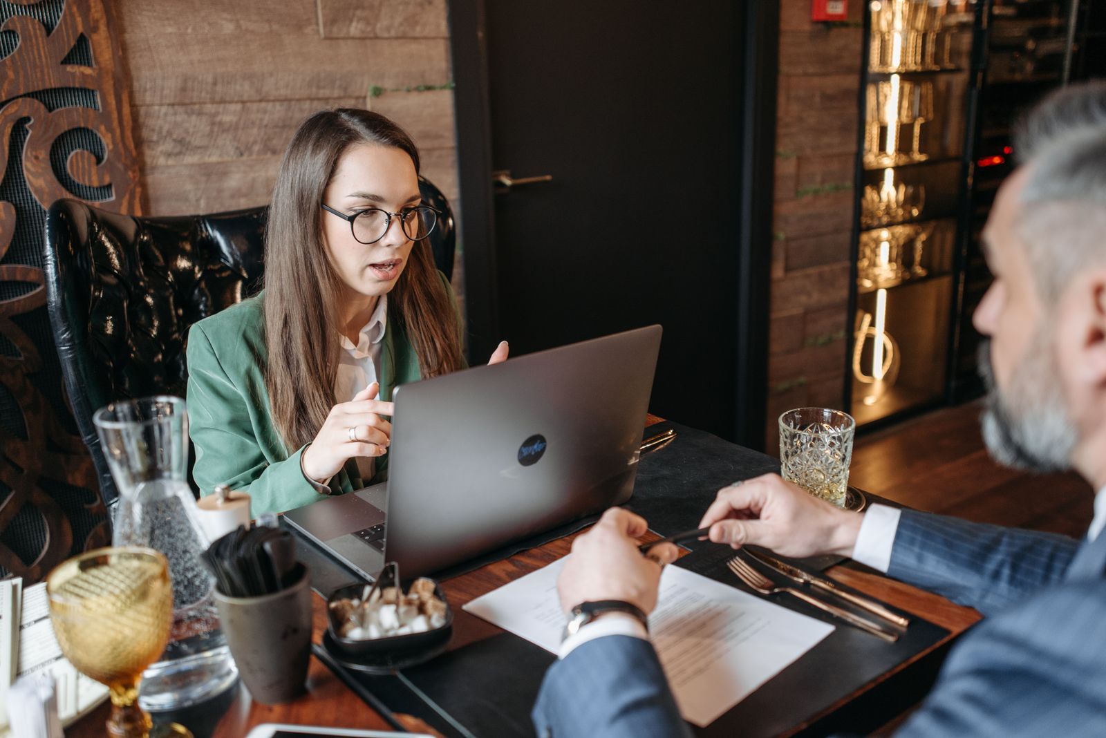 A consultant with a laptop talking with a client over a working lunch