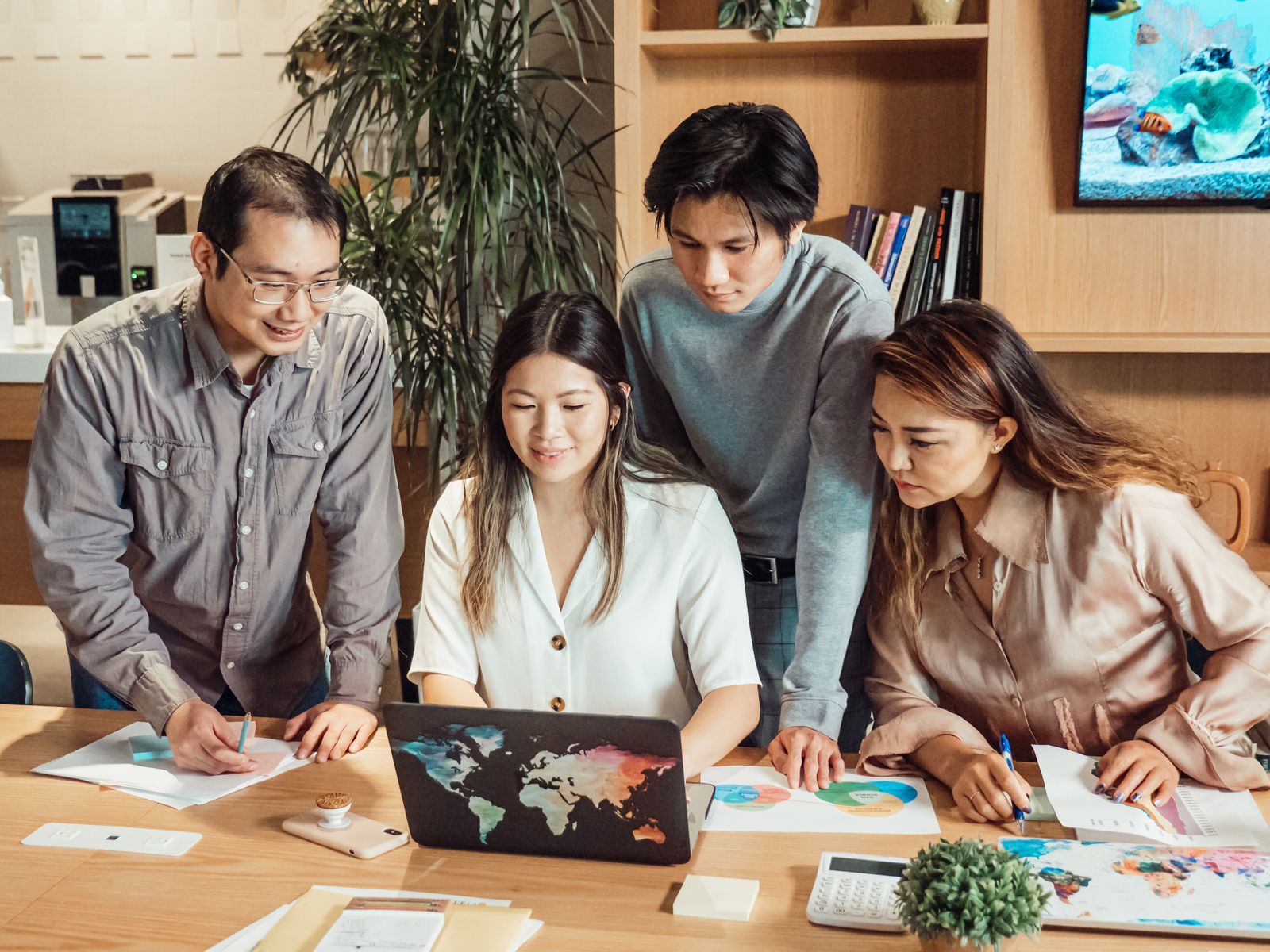 A product team gathered around a laptop and printed charts